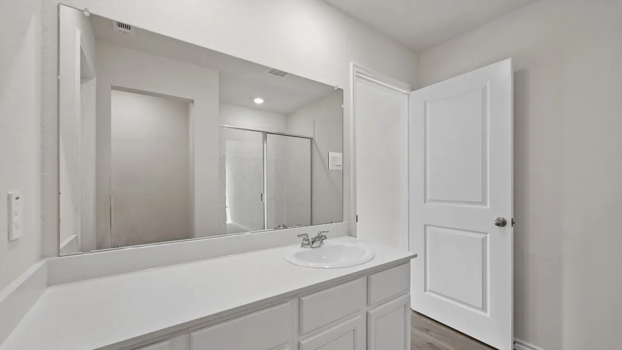 White vanity with a built-in sink, chrome faucet, and expansive wall-mounted mirror