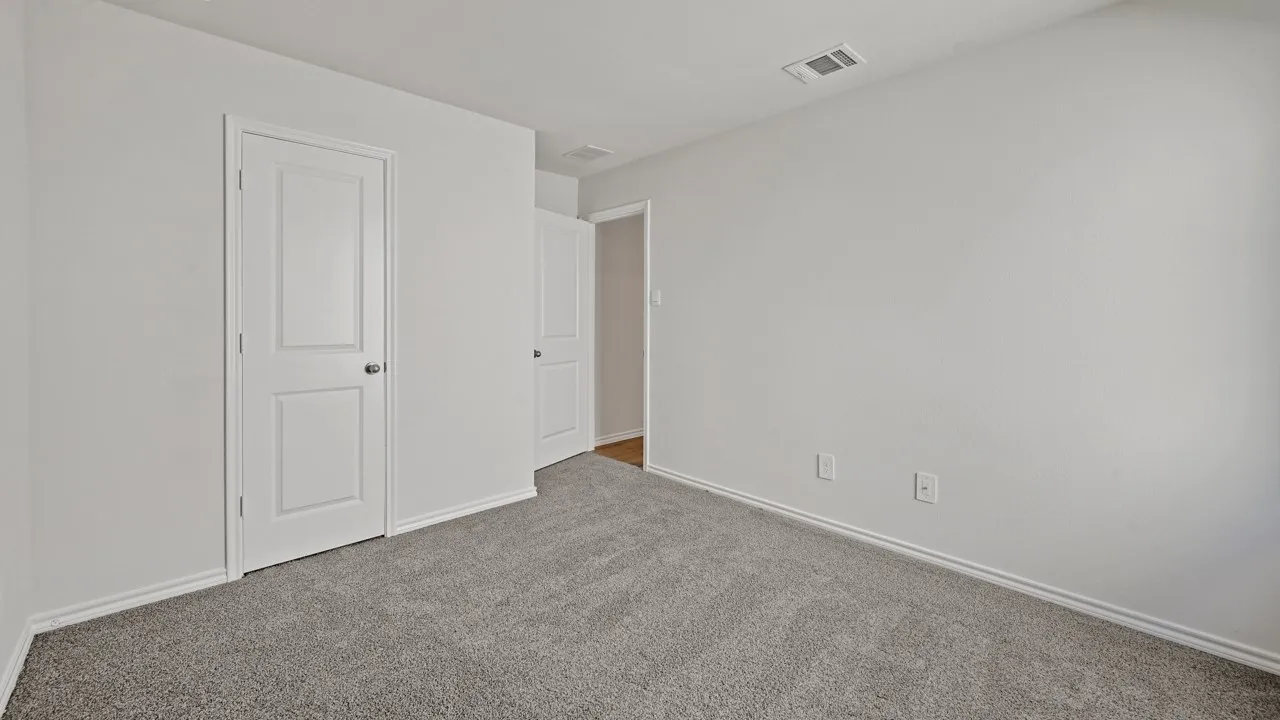 Neutral-toned room featuring grey textured carpeting and white baseboards