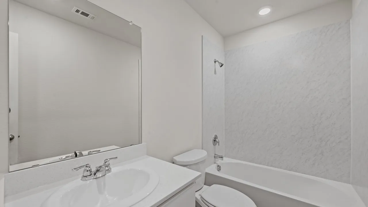 Bathroom featuring a white vanity with an integrated sink, chrome faucet, and a large wall-mounted mirror