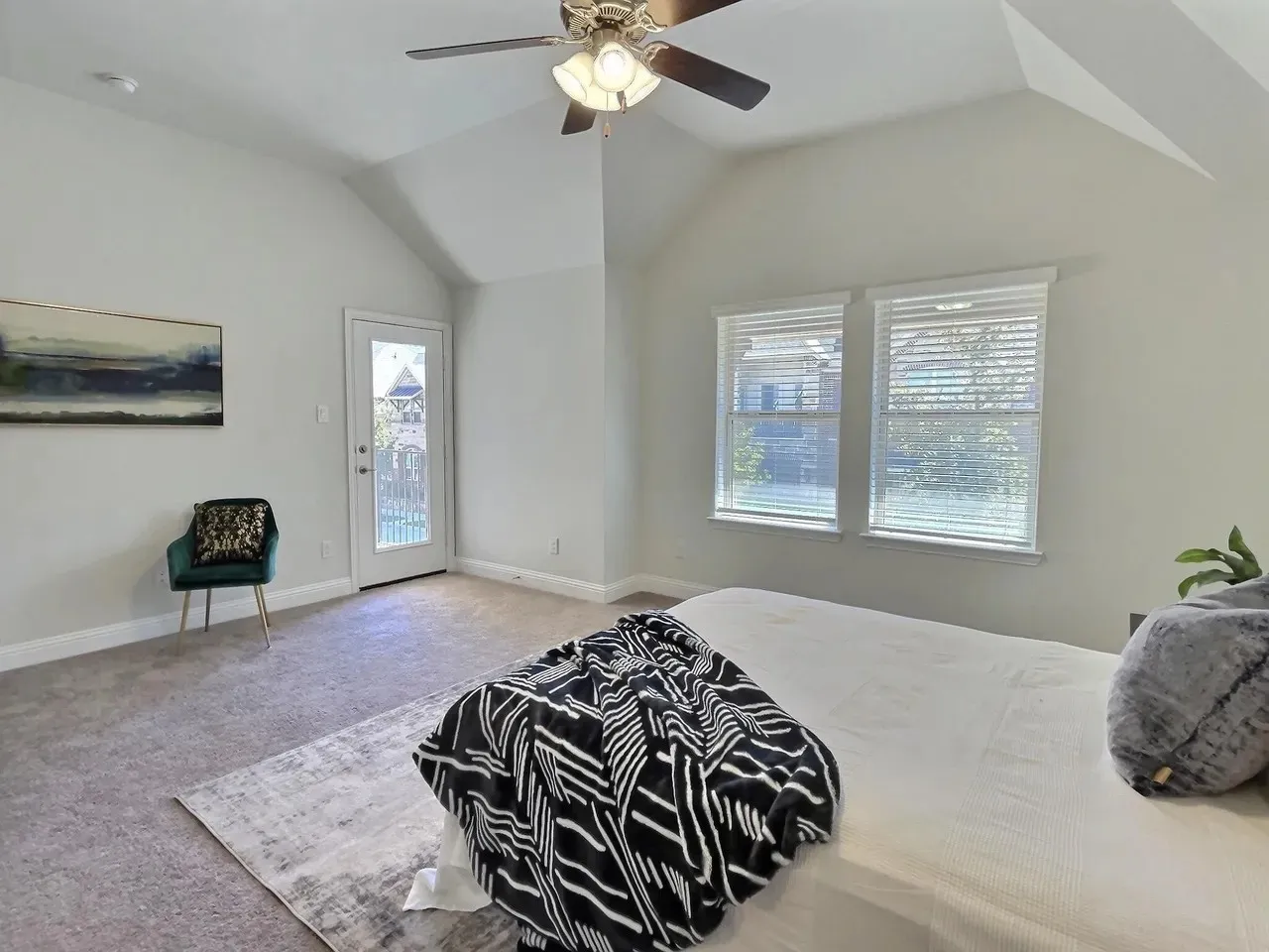 Vaulted ceiling with an attached ceiling fan, dual windows with blinds, and a glass-paneled door