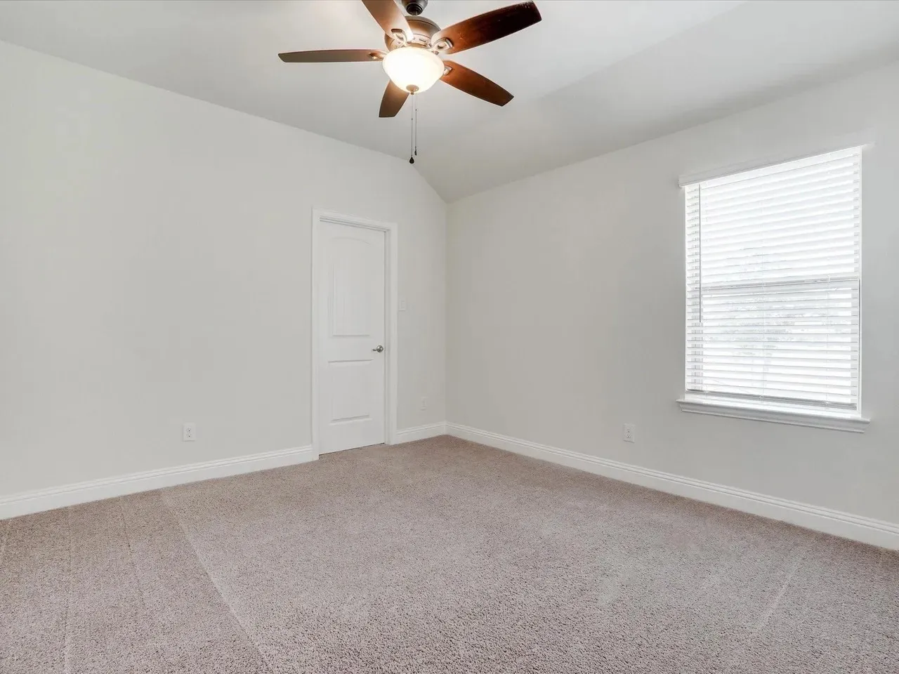 Vaulted ceiling with an attached ceiling fan, neutral carpet flooring, and a white window with blinds