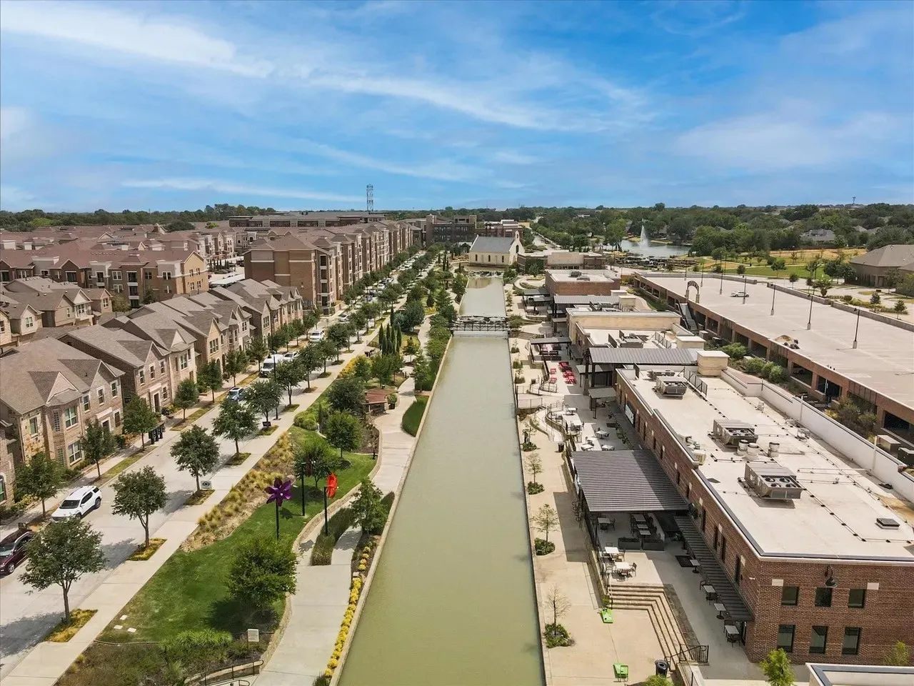 Mixed-use development featuring a canal, residential structures, commercial buildings, and surface parking