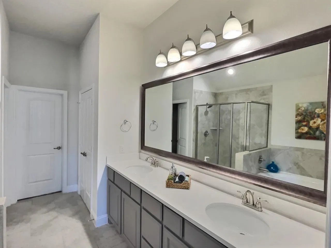Dual vanity with white countertops, undermount sinks, and gray cabinetry