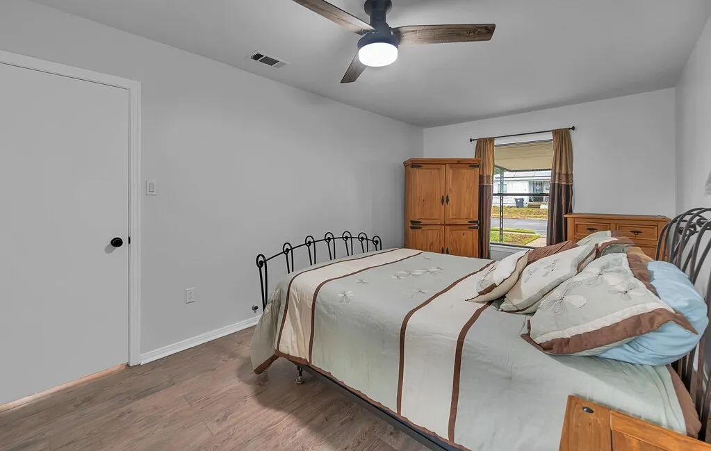 Wood-finish flooring, ceiling fan with integrated lighting, window with exterior street visibility, and painted walls