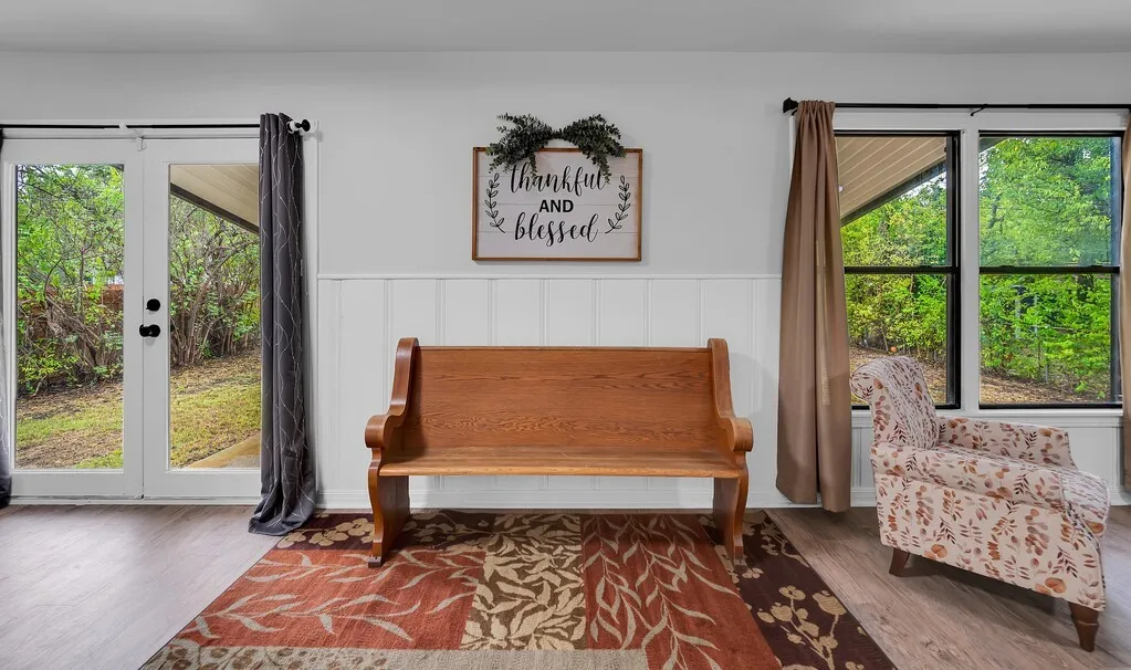 White wainscoting accenting light-toned walls, wood-finish flooring, and a double French door with black hardware