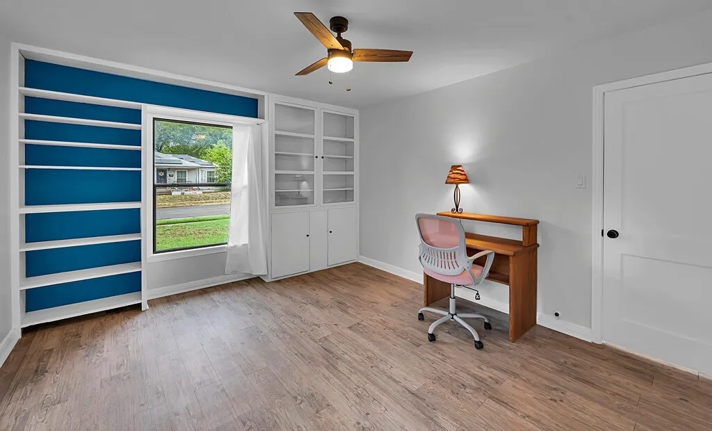 Built-in shelving, built-in cabinetry, wood-finish flooring, ceiling fan, white paneled door
