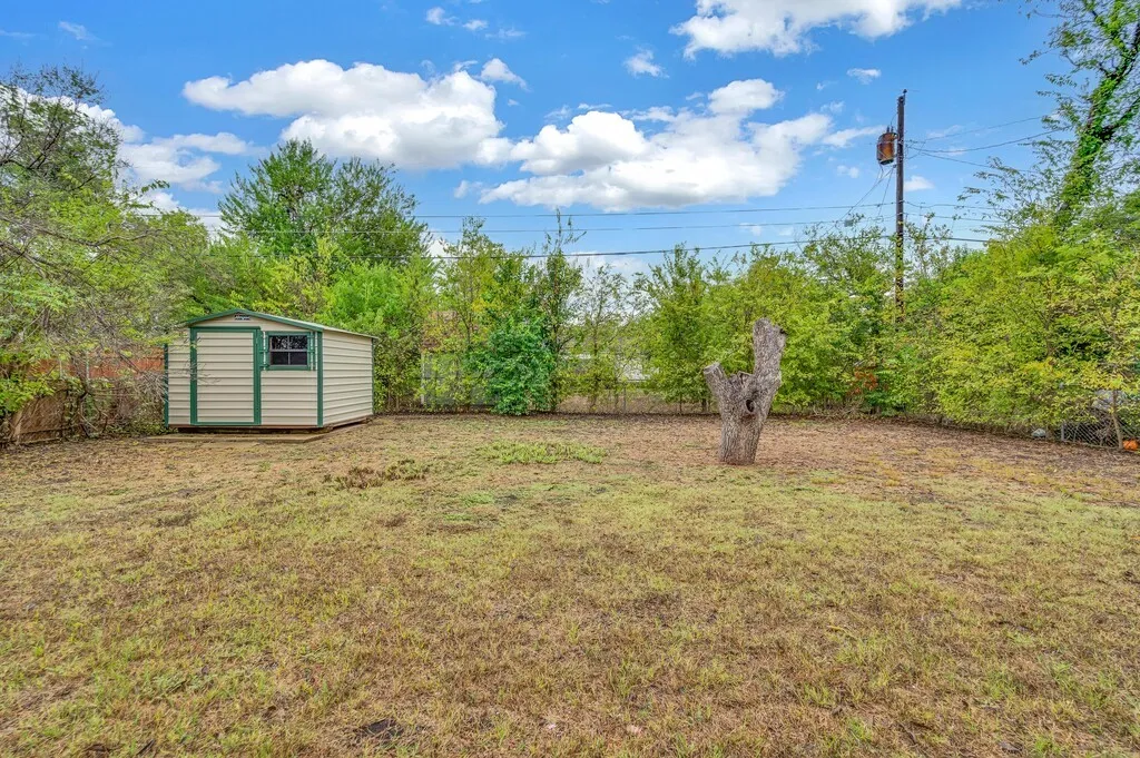 Expansive yard with mature perimeter landscaping and a detached storage shed