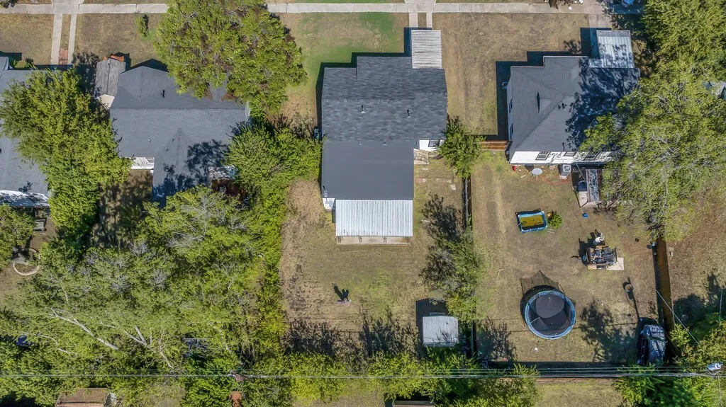 Property featuring a dark shingle roof, a fenced backyard, and mature trees