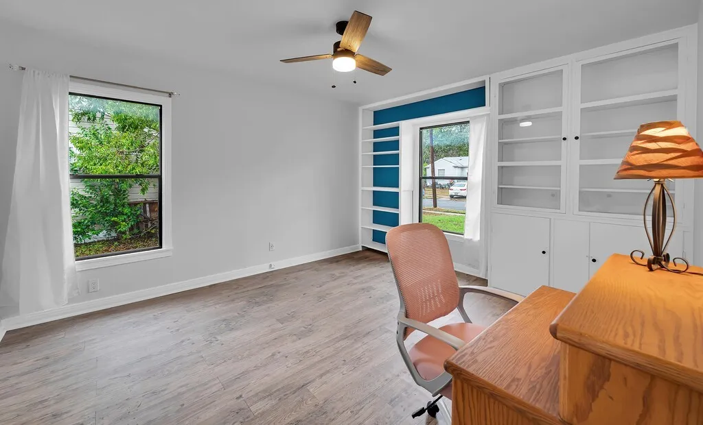 Wood-finish flooring, ceiling fan, built-in shelving, white trim, and light-colored walls