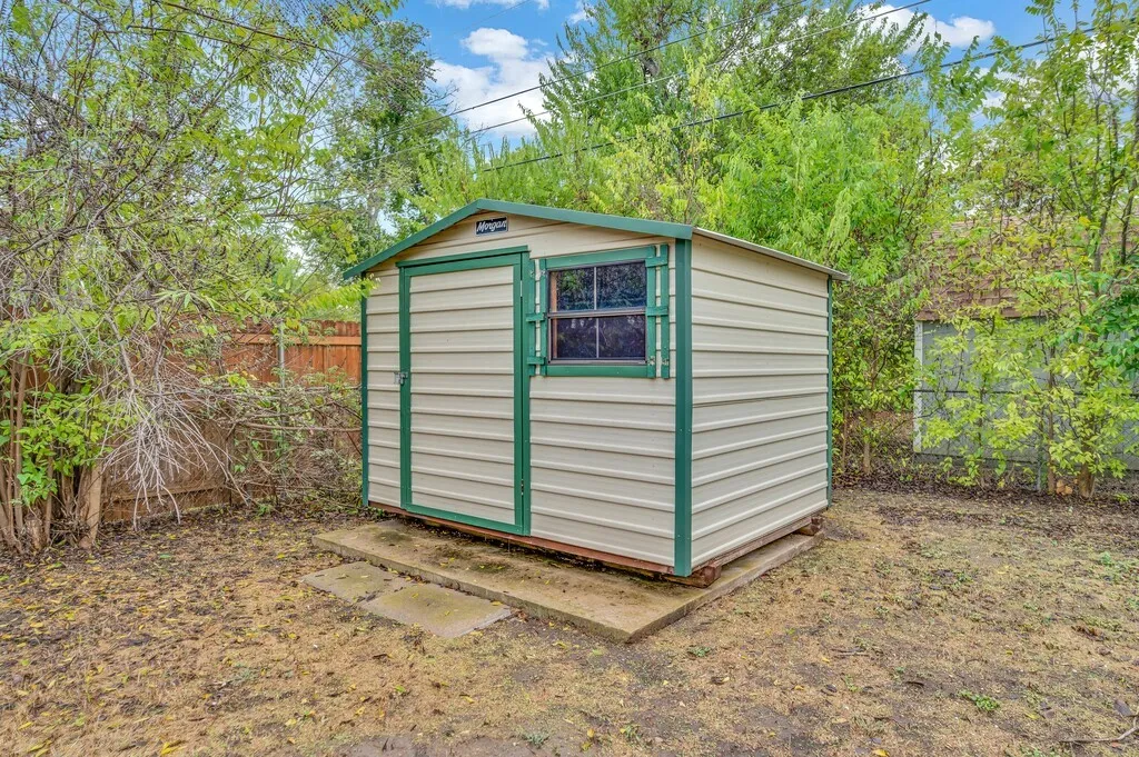 Metal storage shed with a panel door, a single-pane window, and a green trim