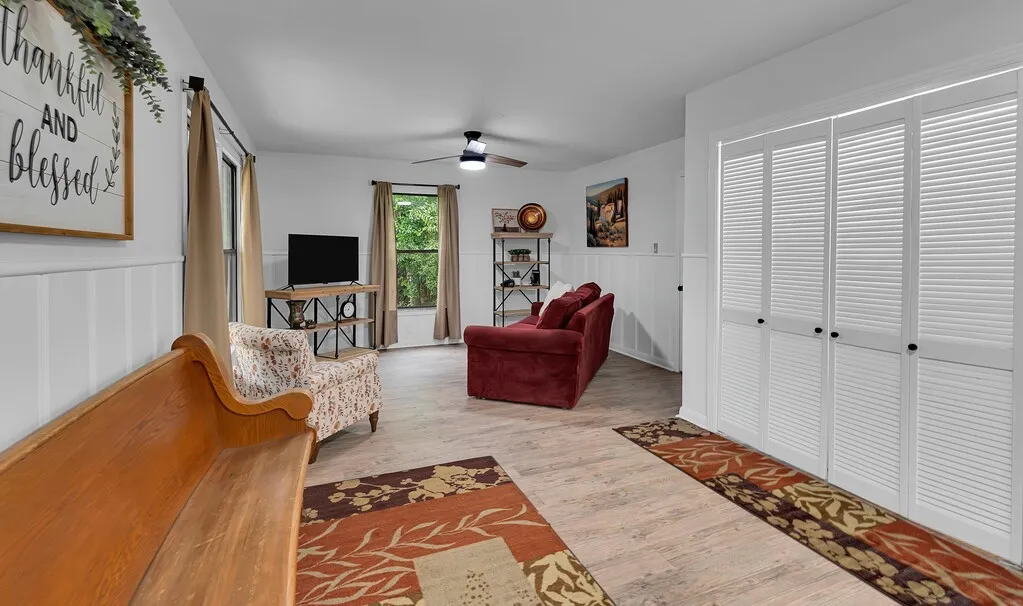 Light wood-finish flooring, white board and batten wall paneling, and an overhead ceiling fan