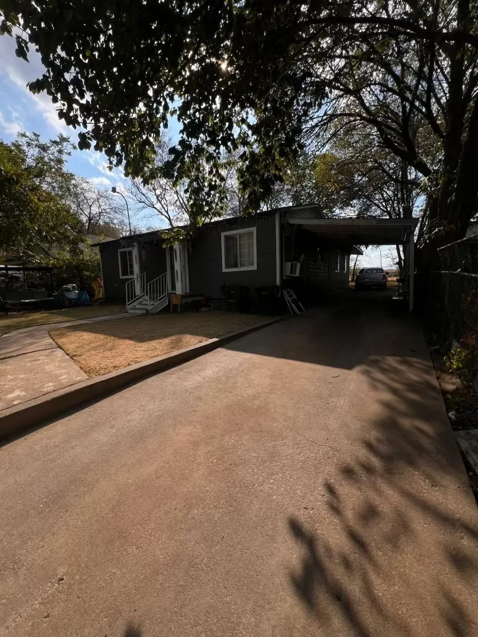 Grey siding exterior with white trim windows and a covered carport