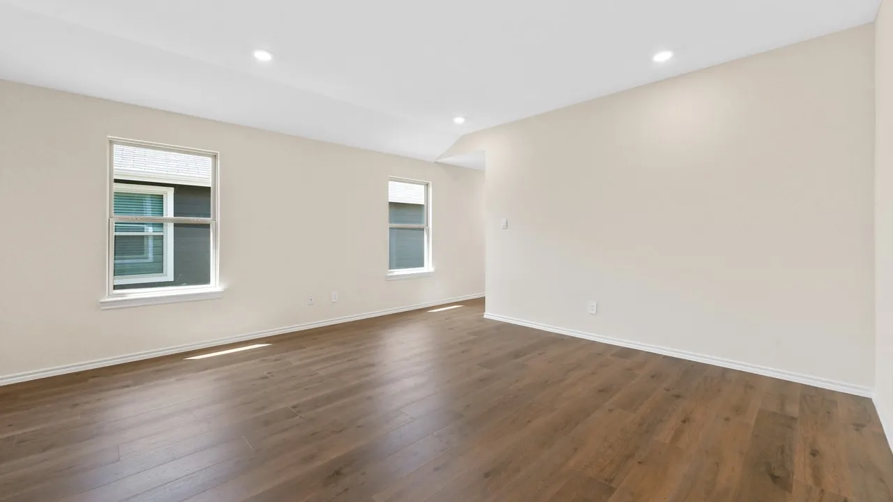 Spacious room featuring wood-finish flooring, recessed lighting, and light-toned walls