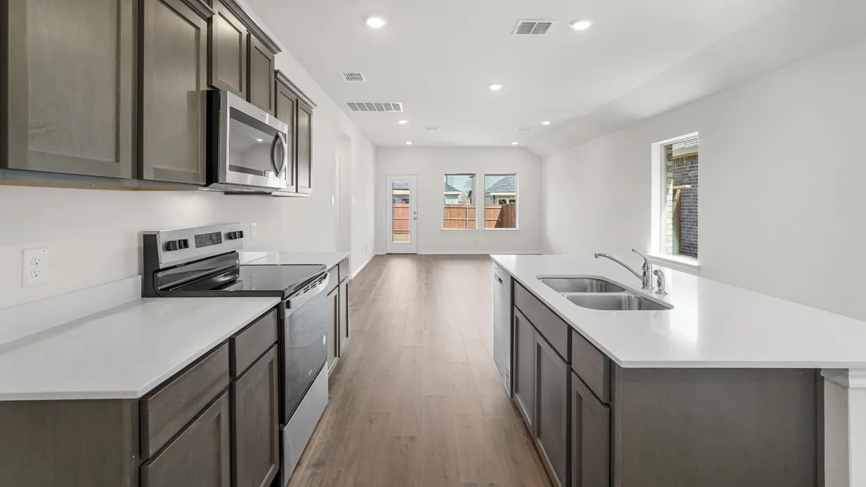 Modern kitchen featuring white countertops, stainless steel appliances, dark wood-finish cabinetry, a double basin sink, and wood-finish flooring
