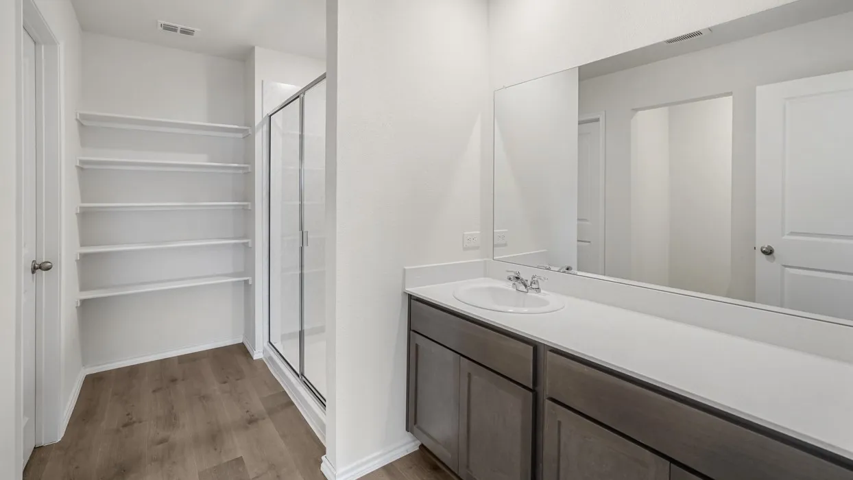 Bathroom featuring a spacious vanity with an integrated sink and an expansive mirror