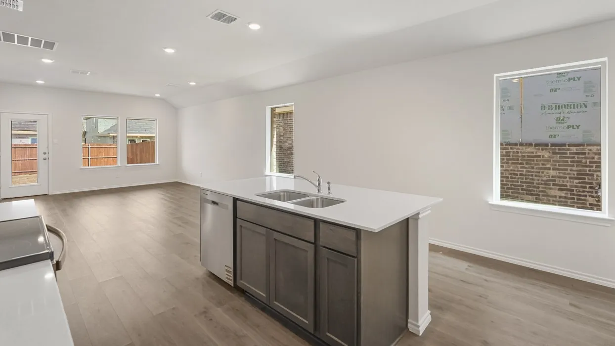 Kitchen island featuring a dual-basin stainless steel sink, integrated dishwasher, and light-toned solid surface countertop