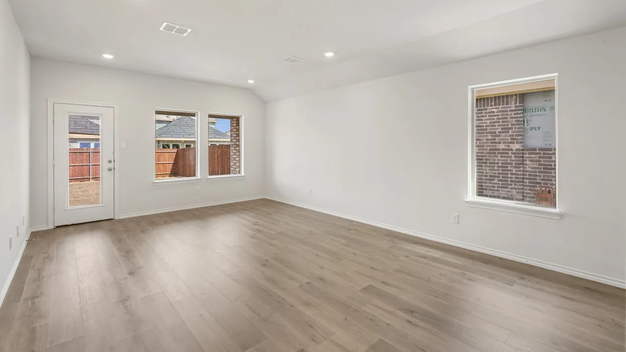 Spacious room featuring light wood-finish flooring, recessed lighting, and a vaulted ceiling