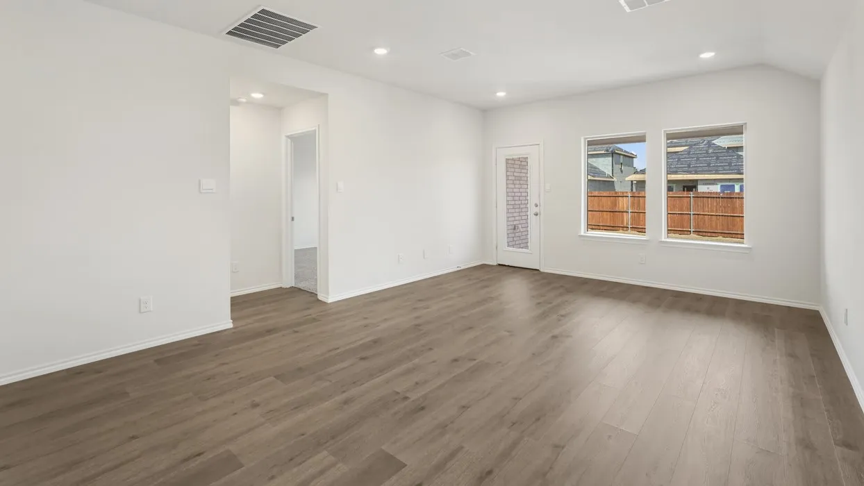 Spacious interior room featuring wood-finish flooring, white walls, and recessed lighting
