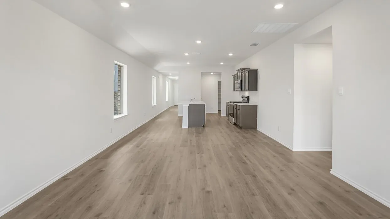 Open-concept living area with wood-finish flooring, recessed lighting, and white baseboards
