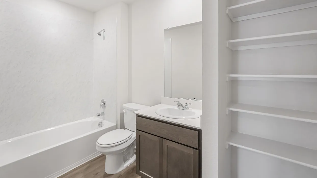 Bathroom featuring a built-in tub with shower, single vanity with a solid surface countertop, wood-finish flooring, and integrated open shelving