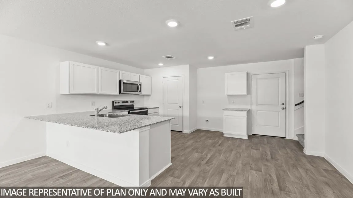 Modern kitchen featuring white cabinetry, stainless steel appliances, and a granite-style countertop with waterfall island edge