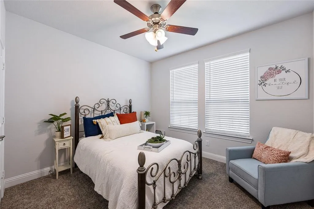 Recessed lighting, ceiling fan with wood-finish blades, two windows with blinds, light gray wall paint, and gray carpet
