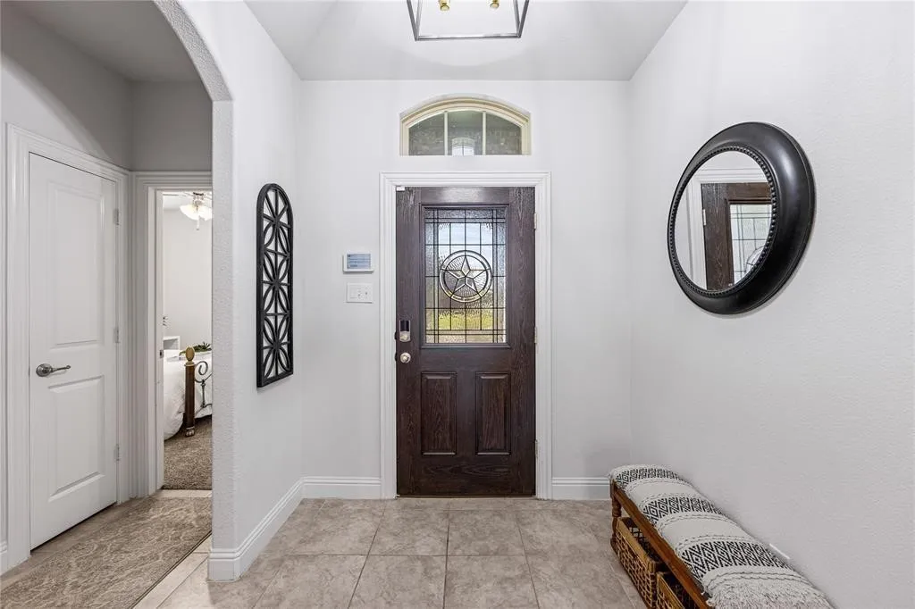 Entryway featuring a dark wood door with decorative glass, an arched transom window, and tile flooring