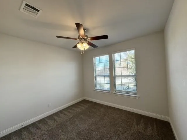 Dual windows with blinds, ceiling fan with light fixture, neutral wall paint, and carpeted flooring