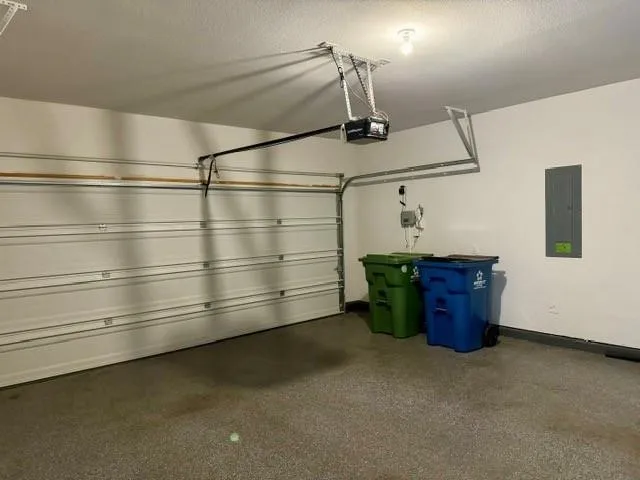 Attached garage featuring a sectional garage door, automatic opener, and finished concrete flooring