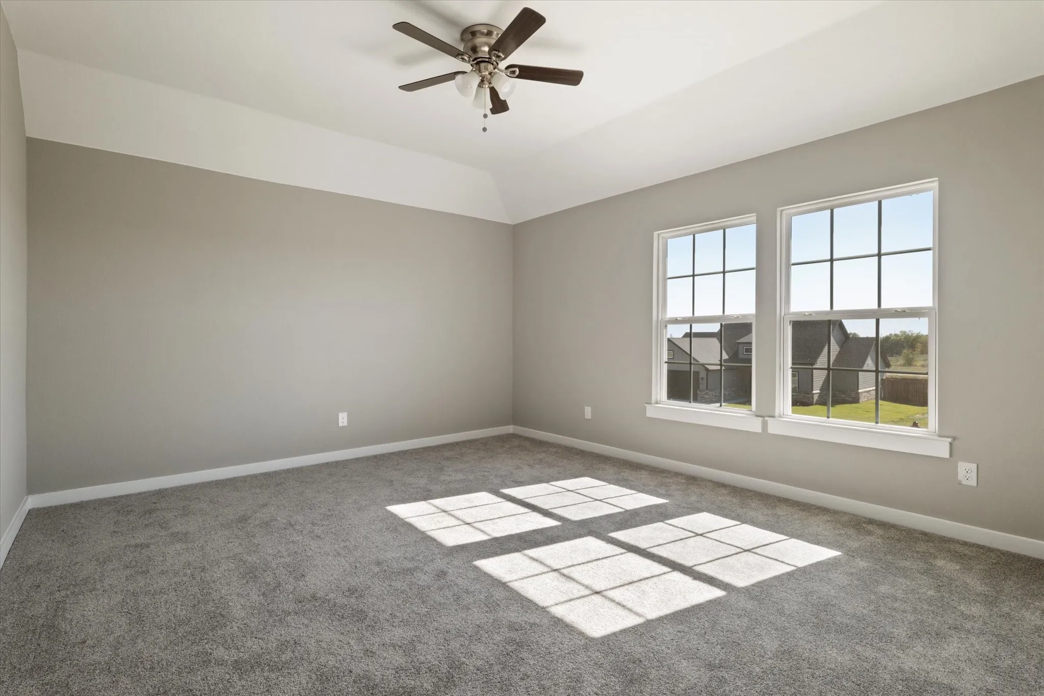 Tray ceiling, two gridded windows, ceiling fan with integrated lighting, wall-to-wall carpeting, and neutral paint finishes