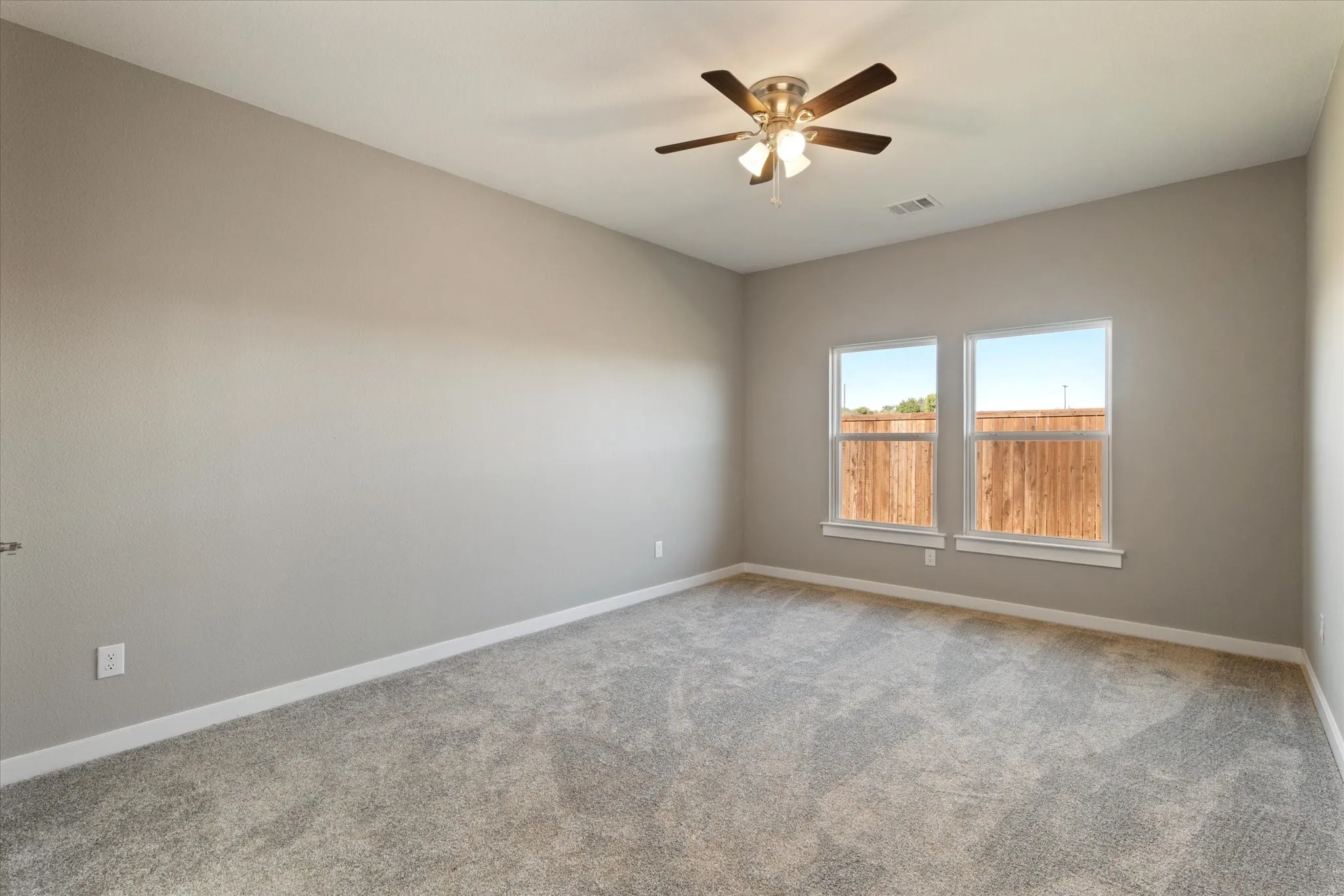 Neutral tone wall paint, light gray carpeting, dual windows, ceiling fan with light, and white trim