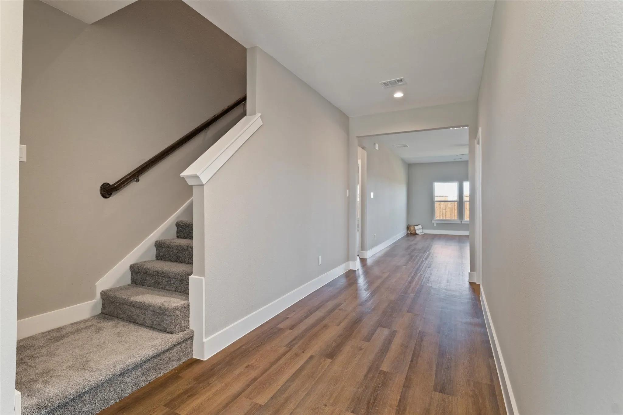 Staircase with carpeted treads and dark-finish handrail