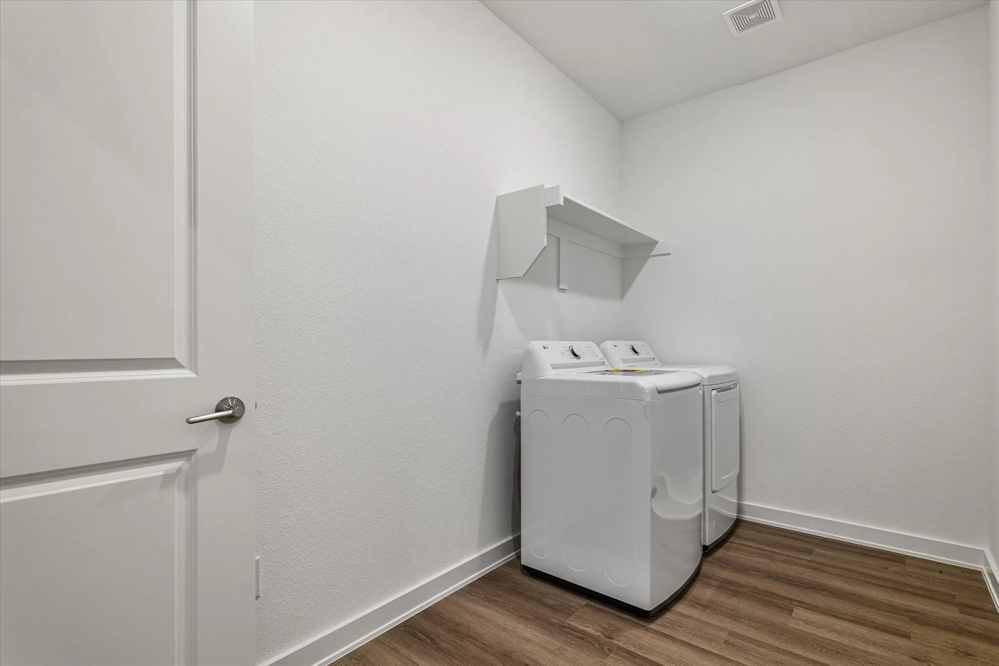 Laundry area featuring wood-finish flooring, white walls, and built-in shelving