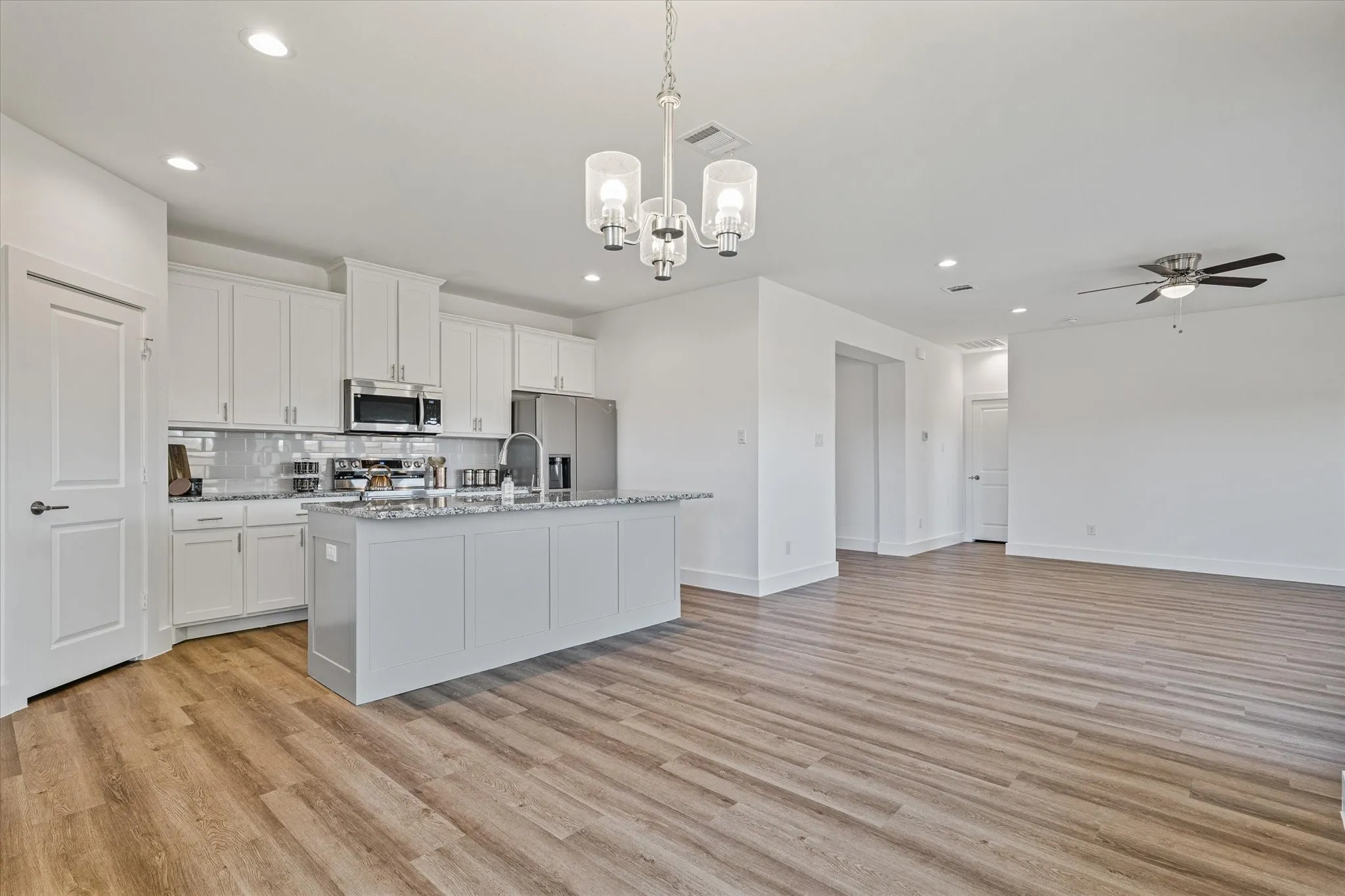 Open-concept living space with wood-finish flooring, recessed lighting, and a ceiling fan