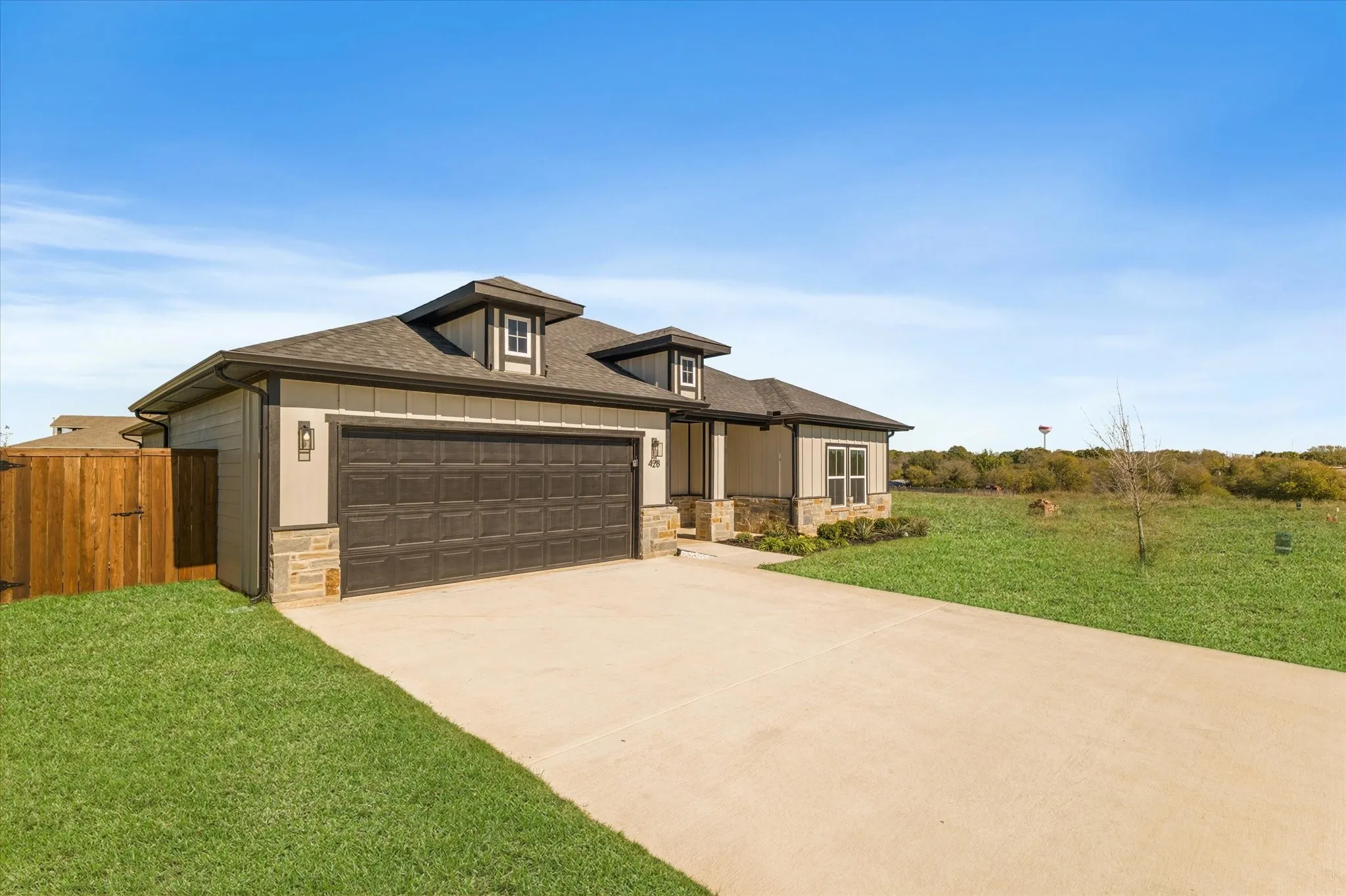 Exterior featuring stone accents, a two-car garage, dormer windows, and a concrete driveway