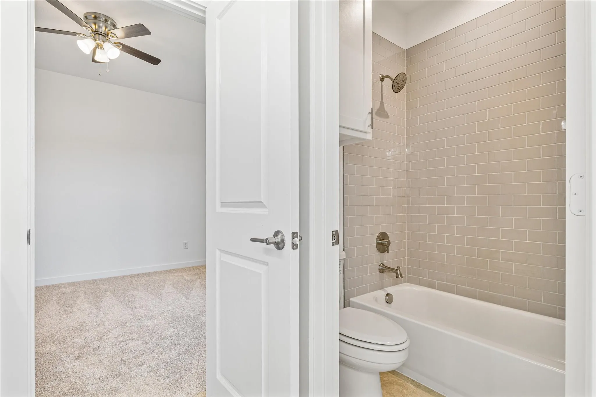 Bathroom with a subway tile shower surround, bathtub, and toilet