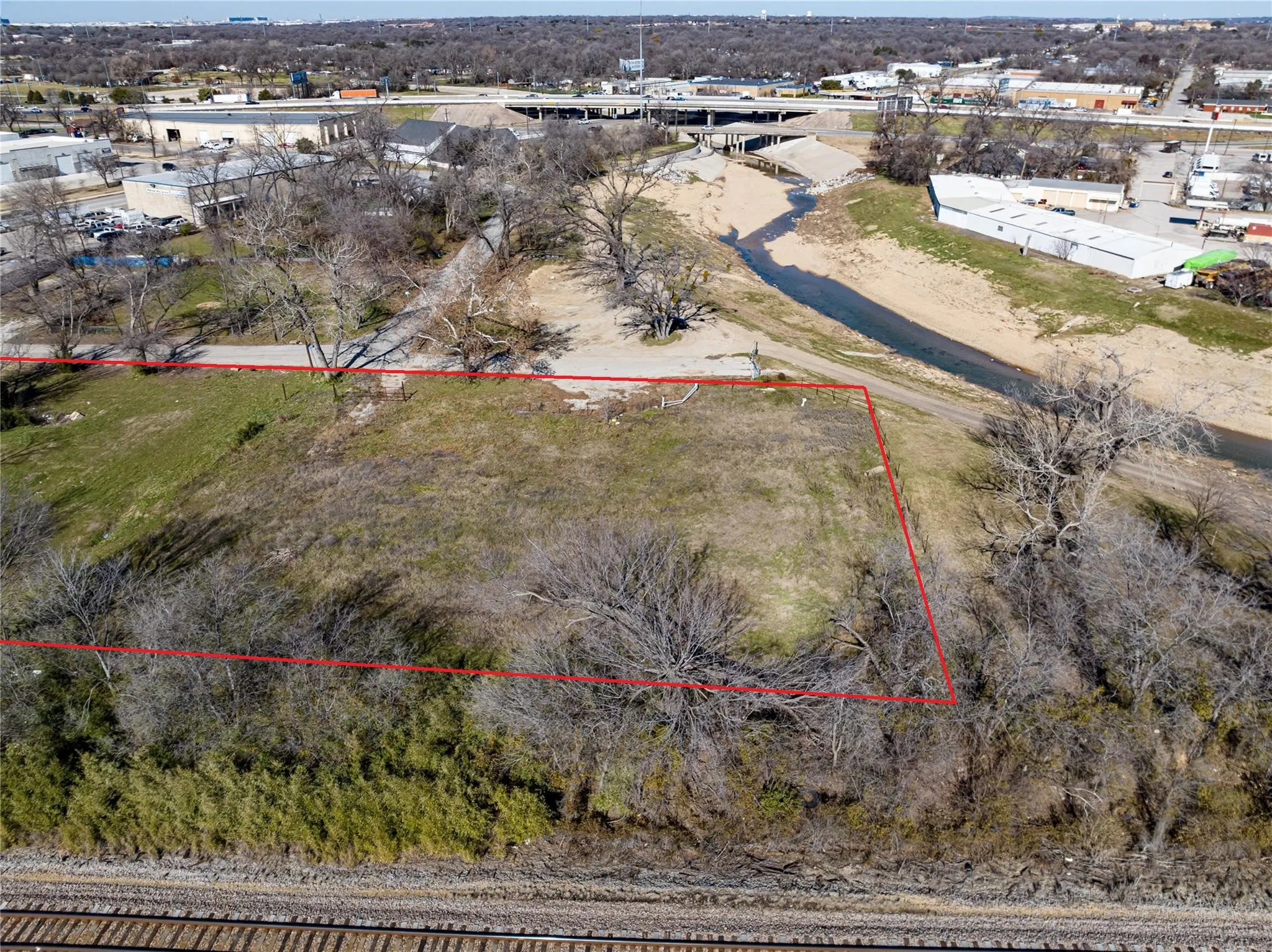 Aerial view of property's location with property parcel outlined and an industrial area
