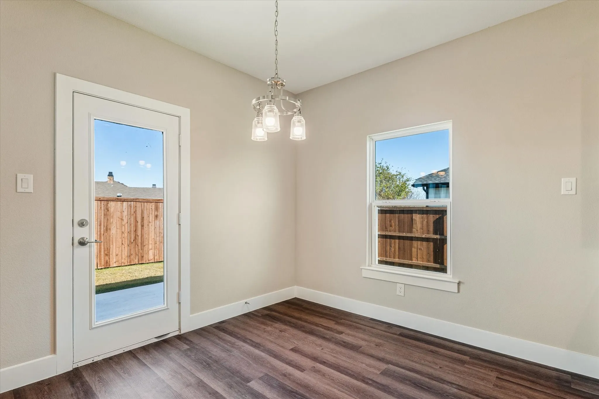 Wood-finish flooring, white baseboards, and a glass-paneled door