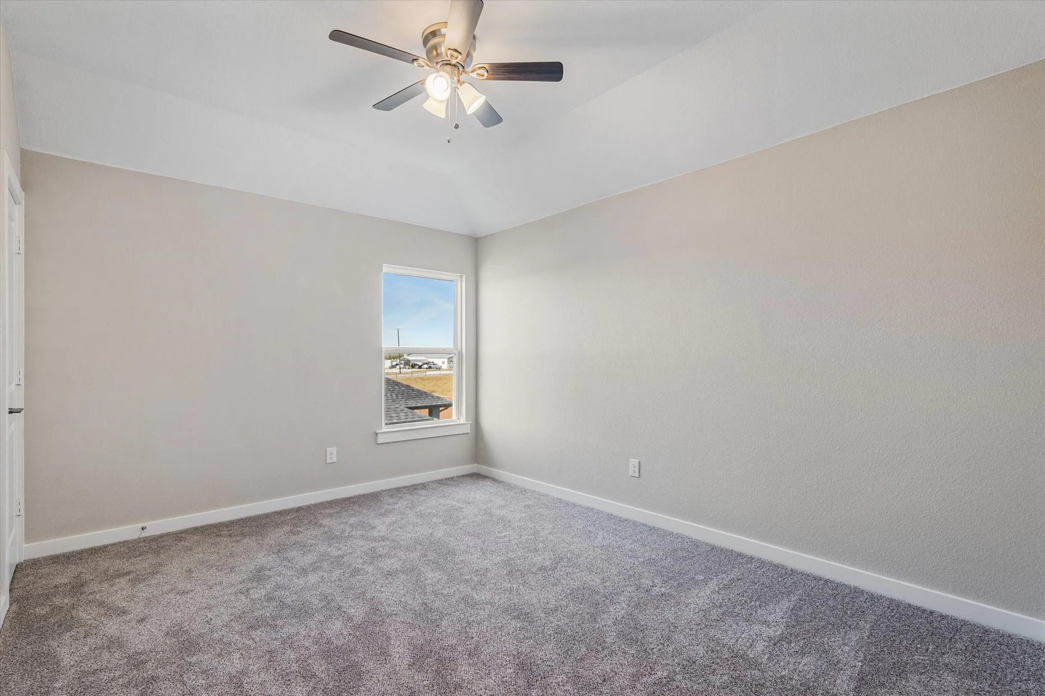 Vaulted ceiling with a flush-mount ceiling fan, neutral wall tones, and plush carpeting