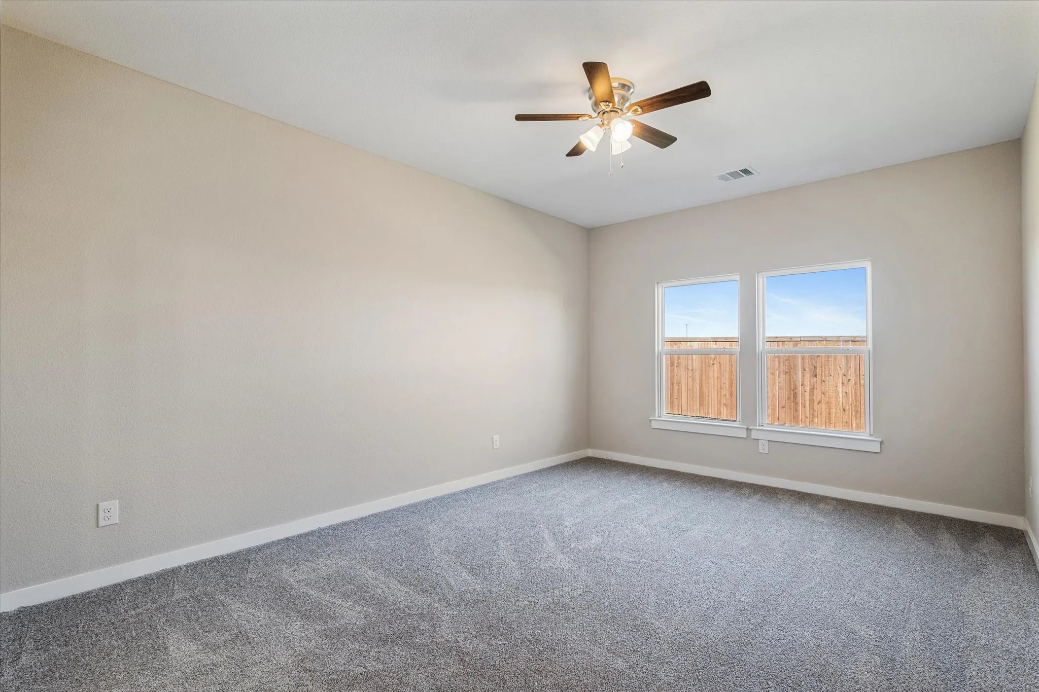 Recessed ceiling with an attached ceiling fan, dual windows, and carpeted flooring