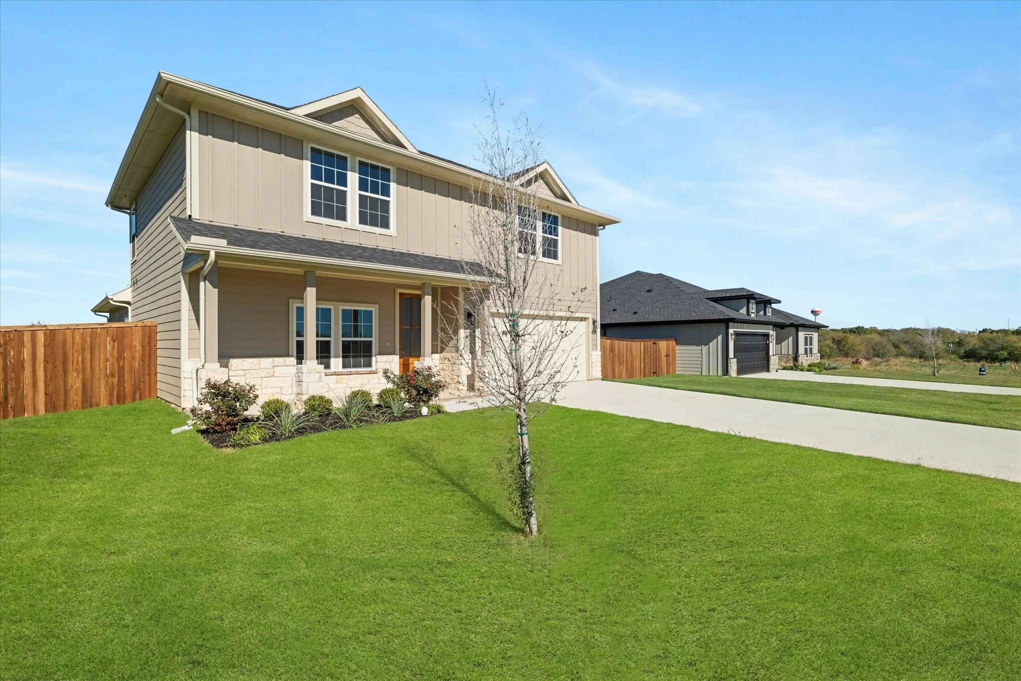 Two-story residence featuring a covered front porch with stone accents, horizontal siding, and a two-car garage
