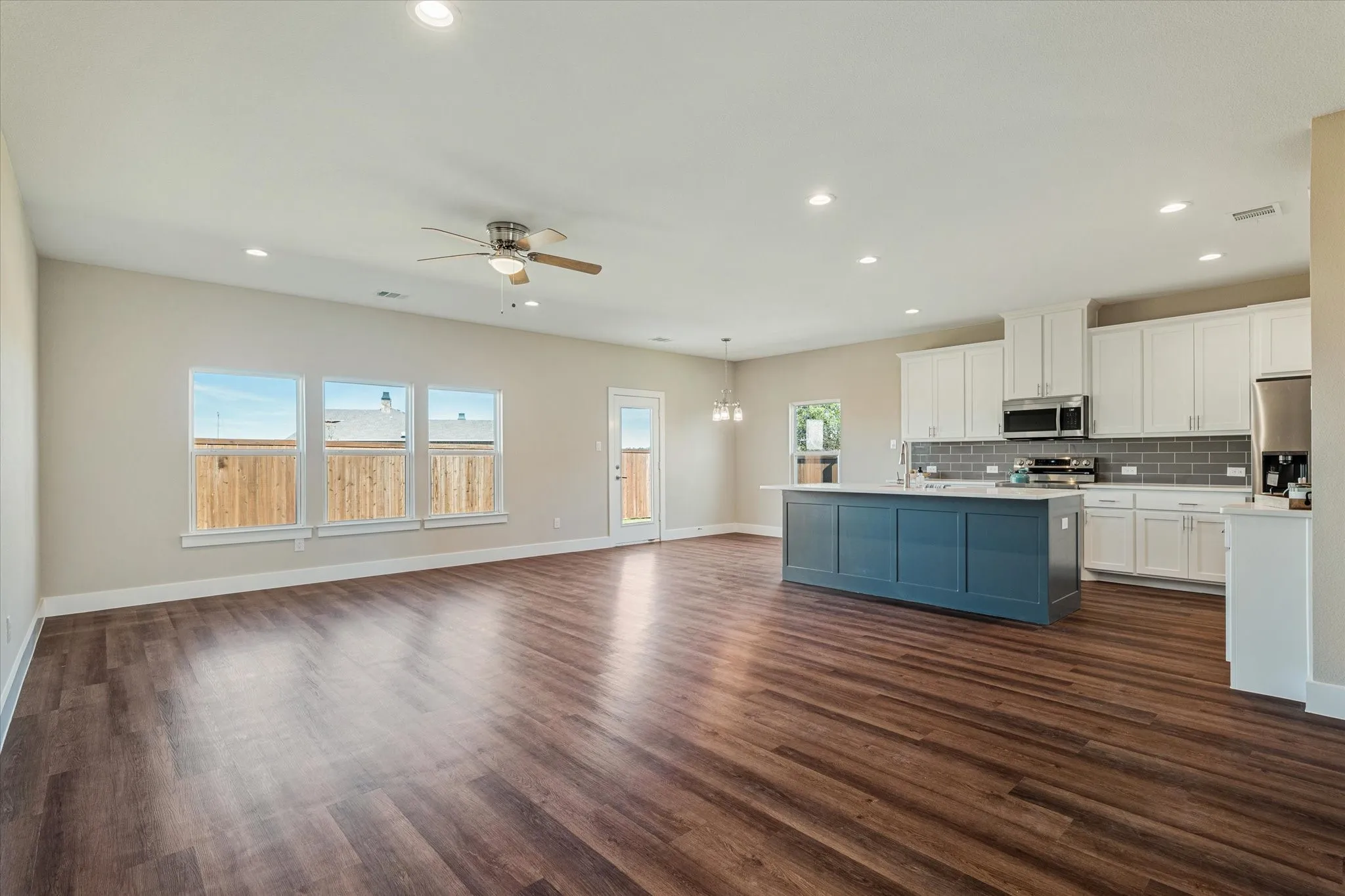 Open-concept living area with wood-finish flooring, recessed lighting, and a ceiling fan