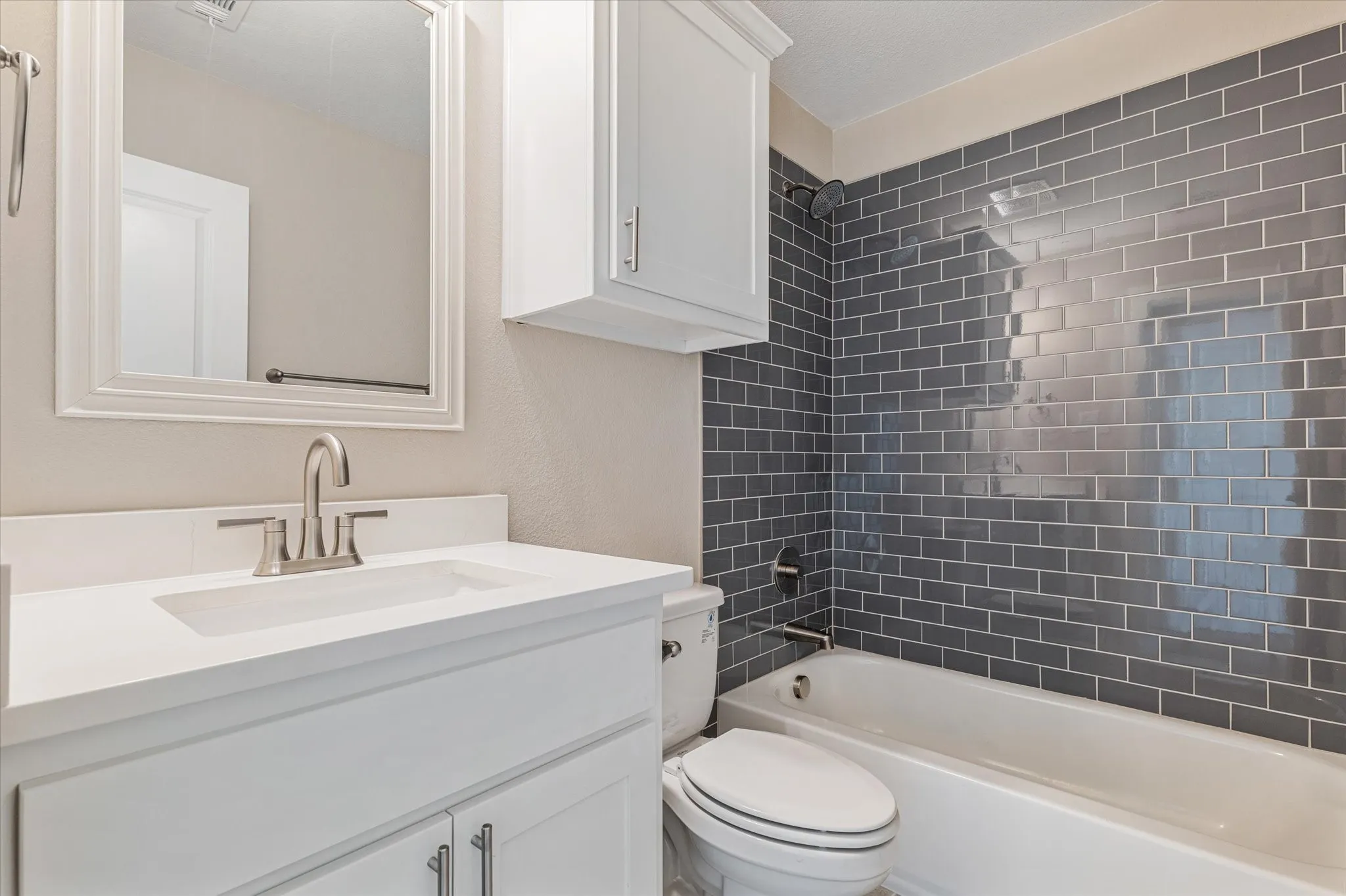 White vanity with integrated sink, brushed nickel faucet, and a wall-mounted medicine cabinet