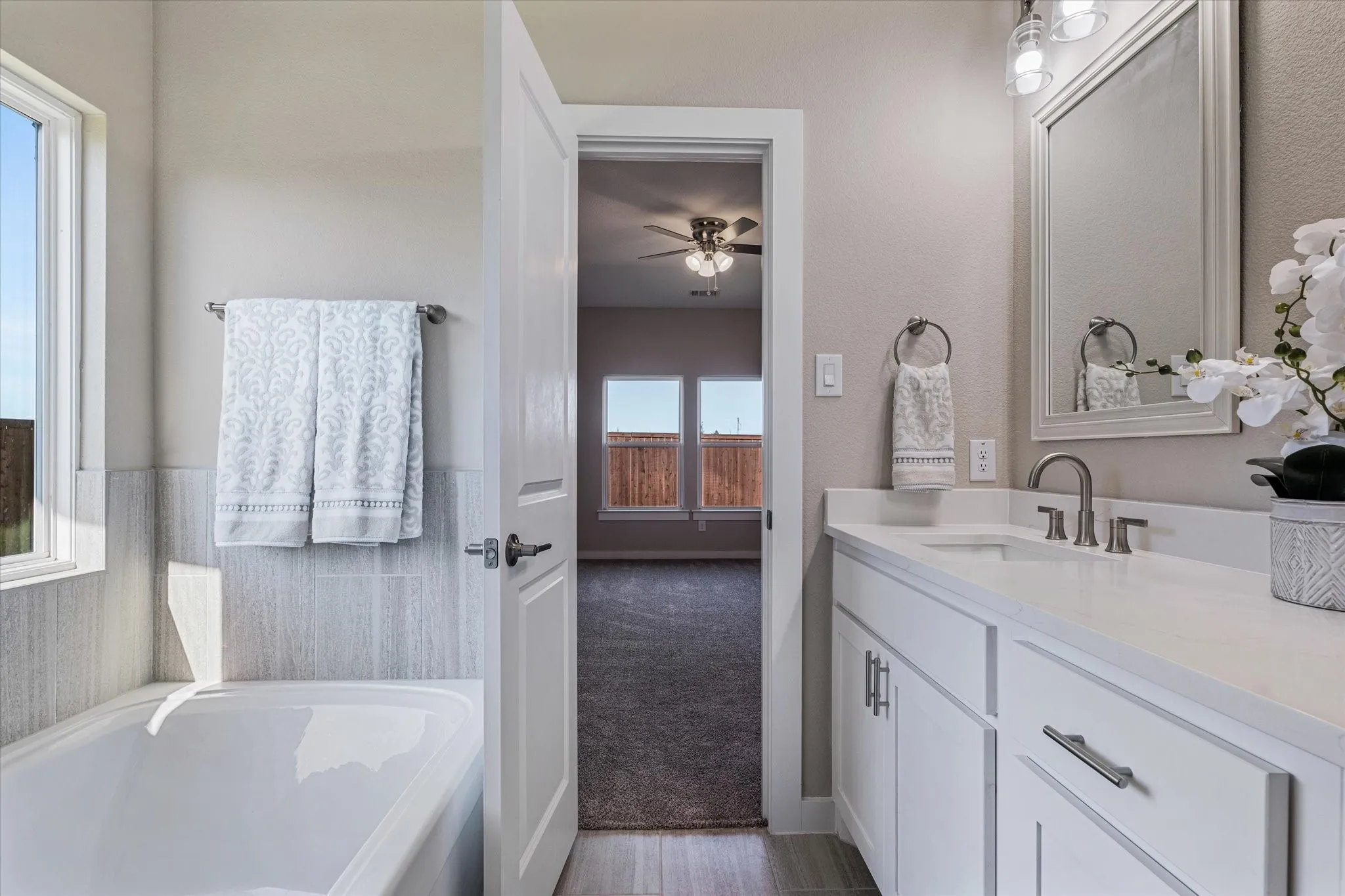 White vanity with dual sinks, brushed nickel fixtures, and a framed mirror