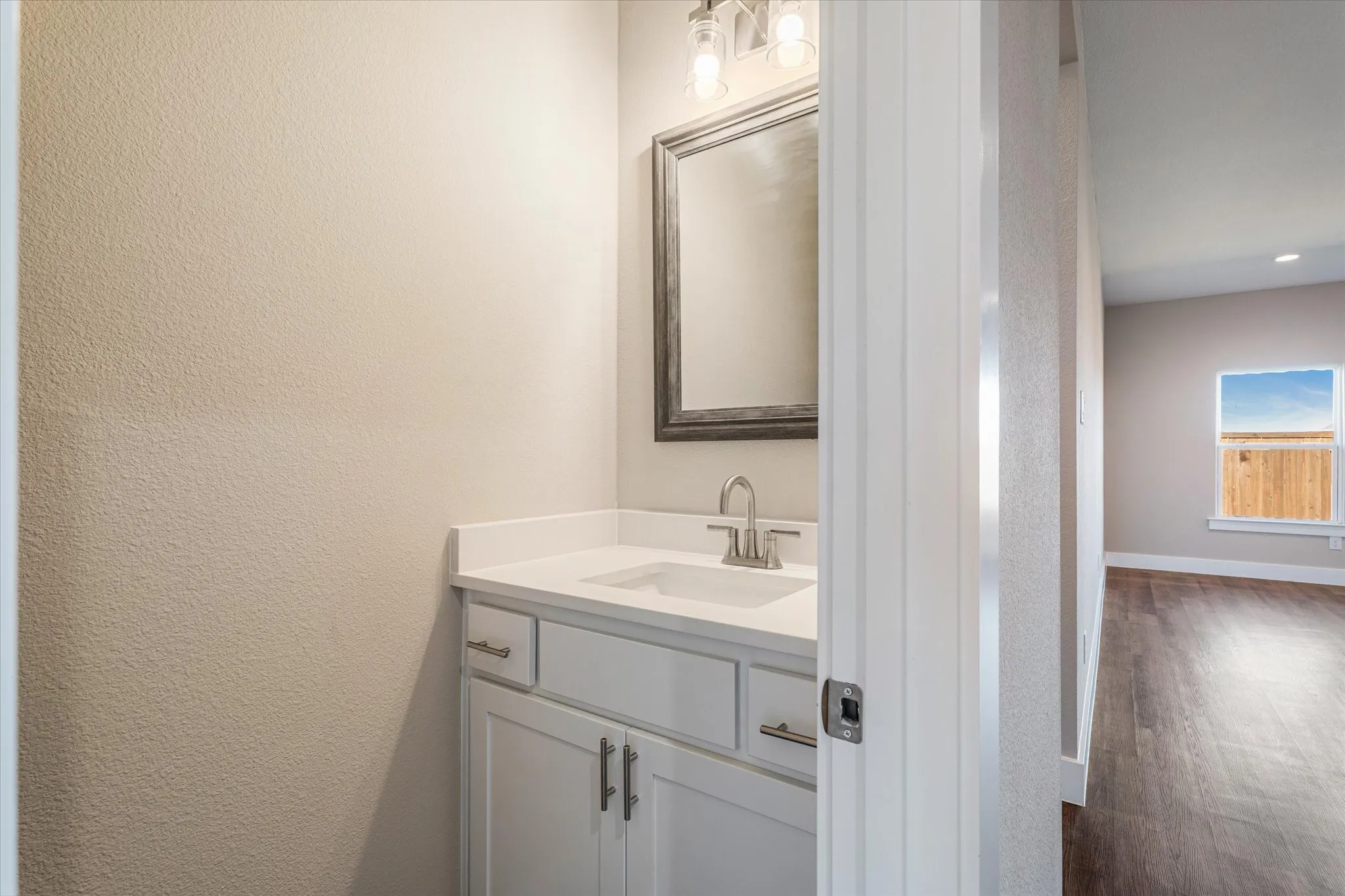 Vanity with white cabinetry, integrated sink, and stainless steel faucet