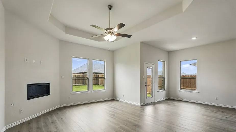 Spacious living area featuring wood-finish flooring, a tray ceiling with a ceiling fan, and recessed lighting