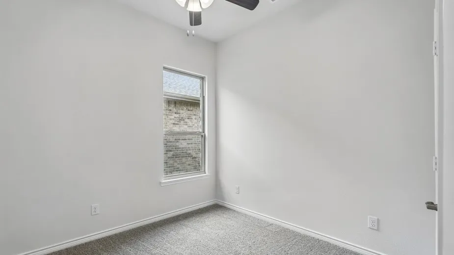 Neutral-toned room with a single window, light gray carpeting, and white baseboards