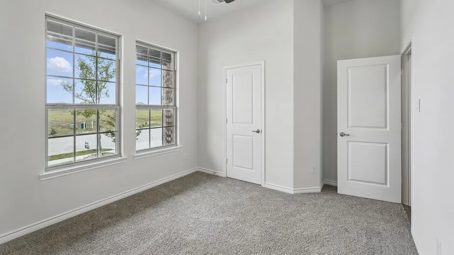 Room featuring two large windows with grid muntins, light gray carpeting, and white baseboards