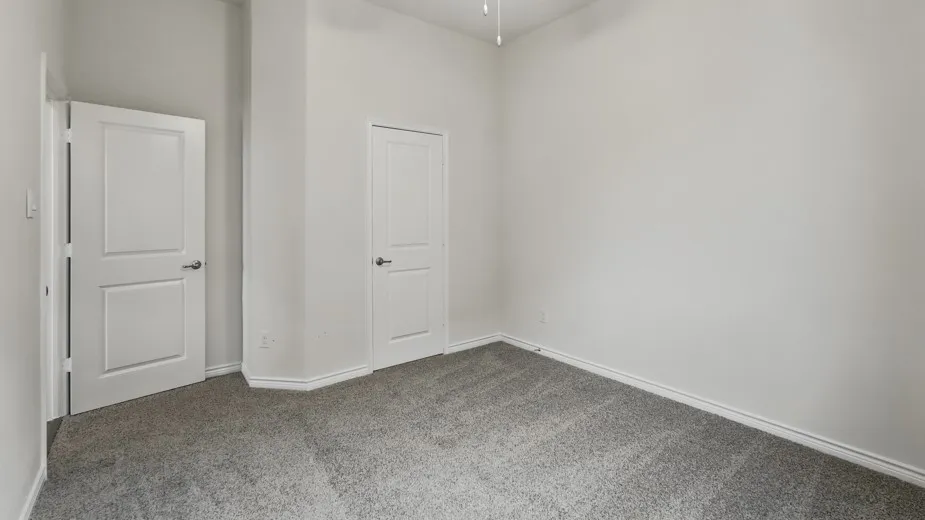 Room featuring neutral-toned walls, gray carpeting, white trim, and two white paneled doors with brushed nickel hardware