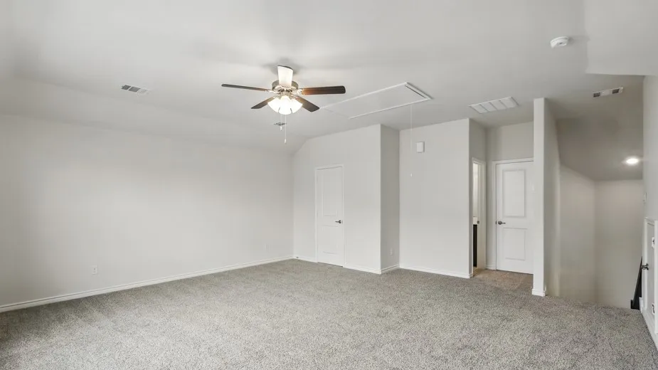 Carpeted room with a ceiling fan, white walls, and multiple doors